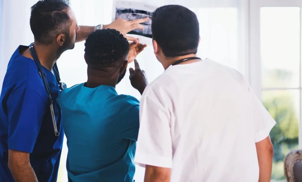 Two locum tenens doctors and a nurse reviewing a radiology film image, collaborating to understand inflammation's role in psoriasis.